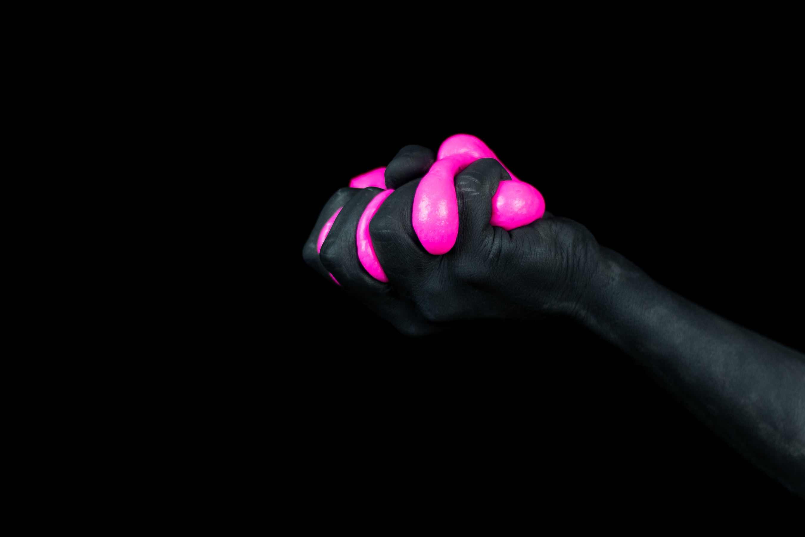 Fondo negro con mano negra sujetando limo rosa fluorescente